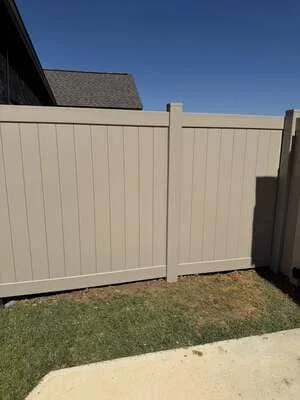 Cream vinyl privacy fence with matching gate installed in residential backyard
