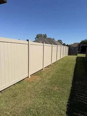 Cream vinyl privacy fence with black posts installed along residential property line