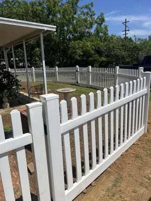 White vinyl picket fence with gate installed around residential property in Headland